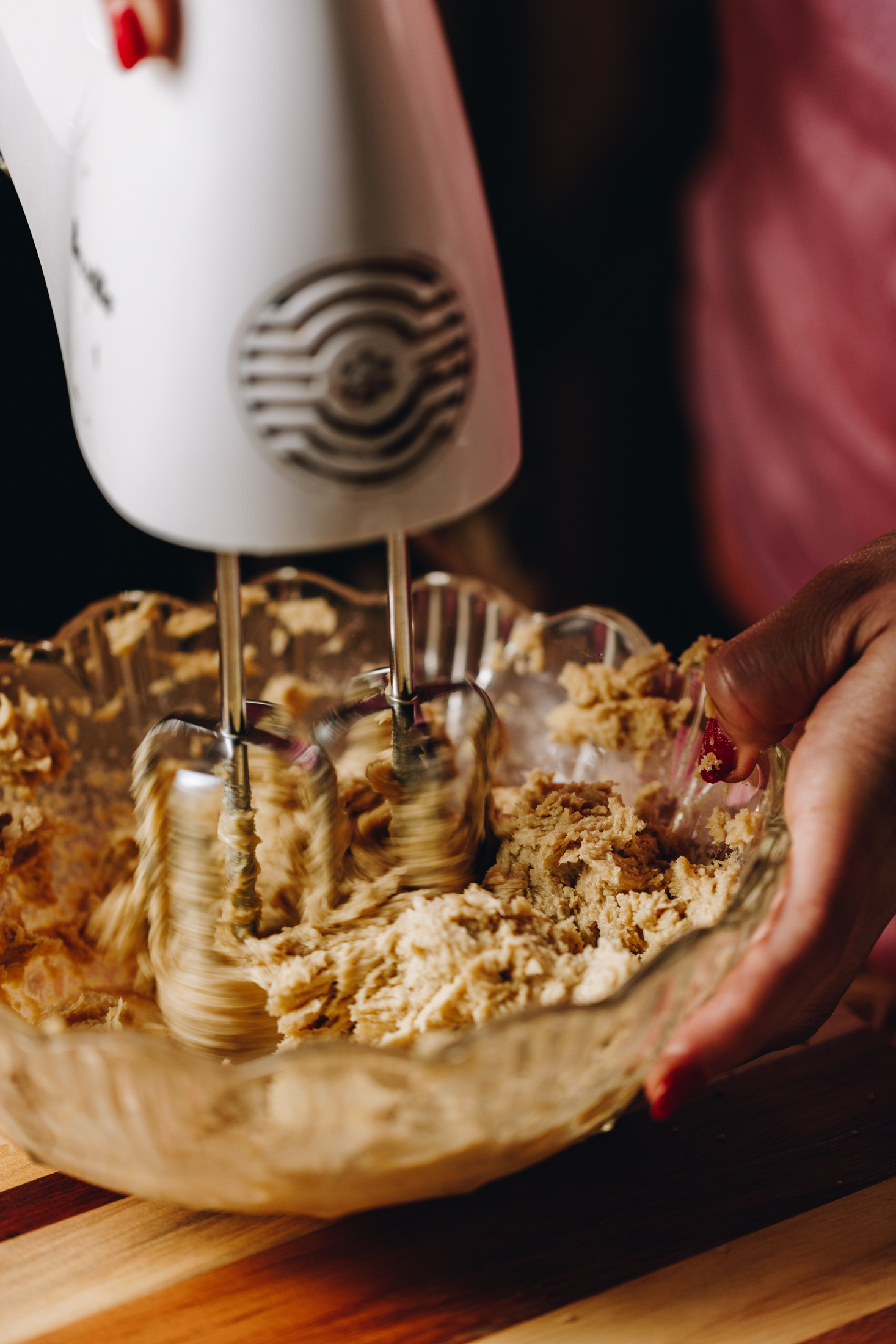 A close of the whipped butter and sugar in a glass bowl that is sitting on a wooden board. 