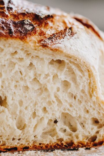 The open rustic bread loaf is cut open to reveal the bread texture.