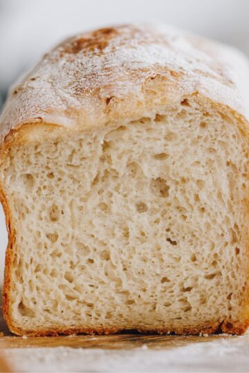 A loaf of no knead bread has been cut open to reveal the soft texture inside.