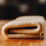 A close up of folded puff pastry on a wooden table.