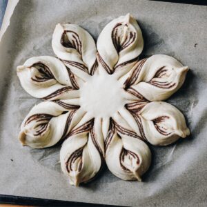 Flat lay shot reveals an unbaked star chocolate bread shaped in to a star on baking paper.
