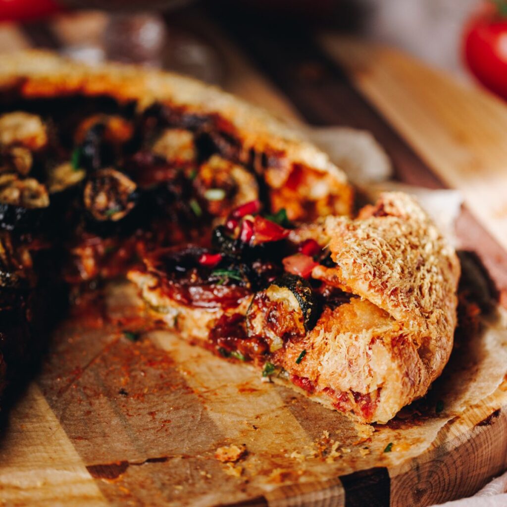 A slice of roasted tomato and courgette galette reveals the vegetables inside the rustic pastry.