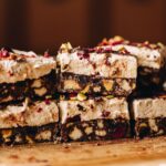 On a wooden board is two layers on no-bake marshmallow hedgehog slice. The biscuit chocolate base and thick marshmallow layer are seen.