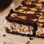 Close up of a slice of no bake marshmallow slice that has a chocolate top with a peanut butter design on top. The marshmallow has textures running through it.
