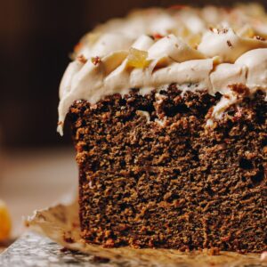 A close up shot of spiced gingerbread loaf shows the loaf texture and the cream cheese frosting on top.