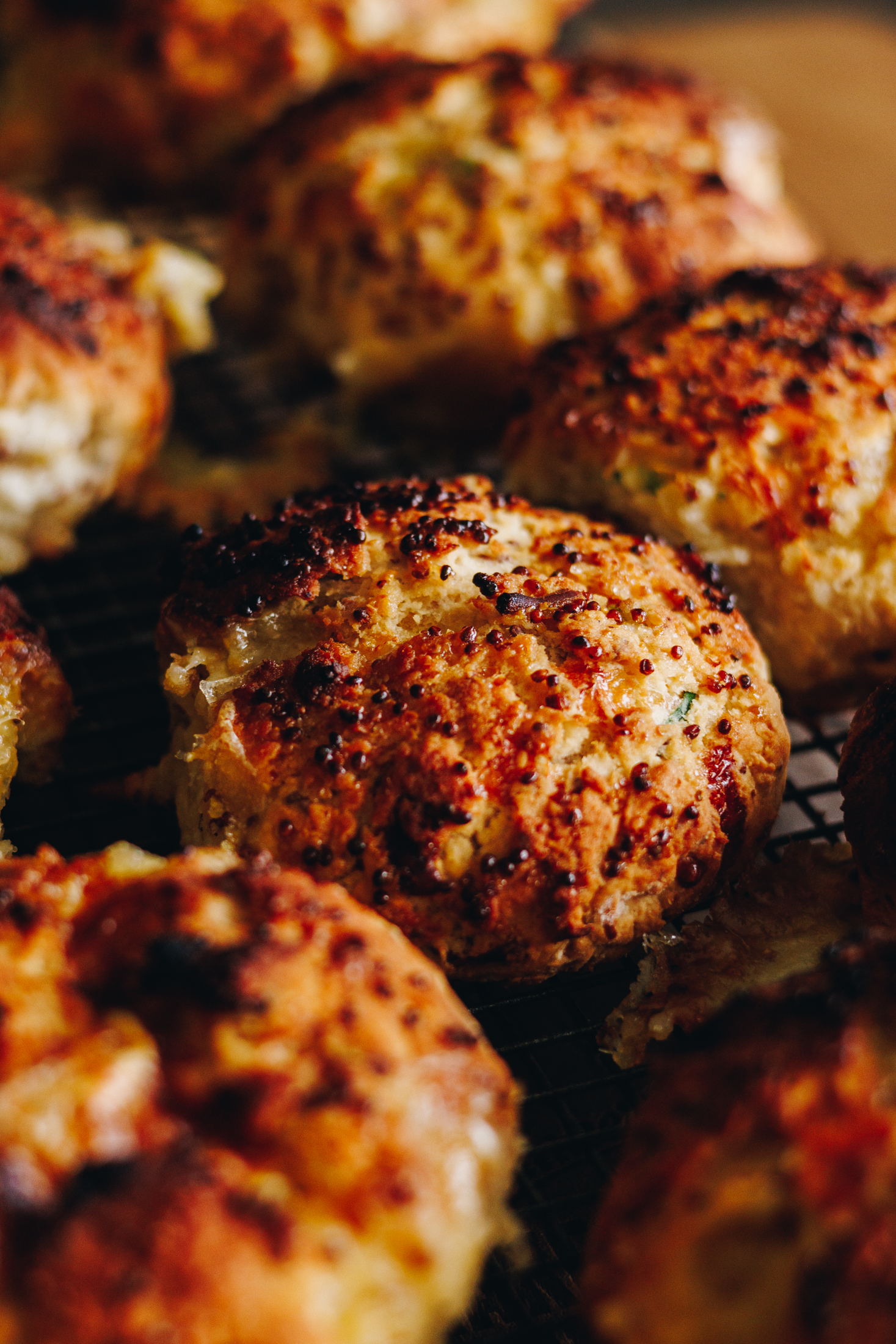 Close up of Brie Stuffed Honey Mustard Scones a wire cooling rack. They are golden and rounded with speckles of wholegrain mustard on top. 