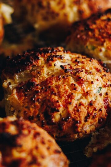 Close up shots of golden baked brie stuffed honey mustard scones with speckles of mustard seeds on top.