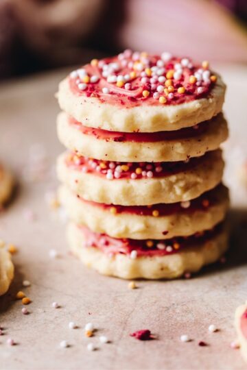 Freshly baked and decorated hundreds and thousands biscuits are piled on top of each other.