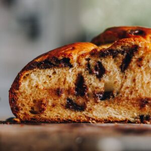 A close up of a baked braided chocolate chip bread that has been cut open to reveal the chocolate chips and bread texture.