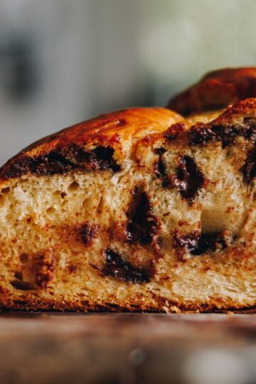 A close up of a baked braided chocolate chip bread that has been cut open to reveal the chocolate chips and bread texture.