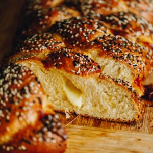 A freshly baked Savoury braided bread has been cut open to reveal the gooey cheese centre and soft bread texture