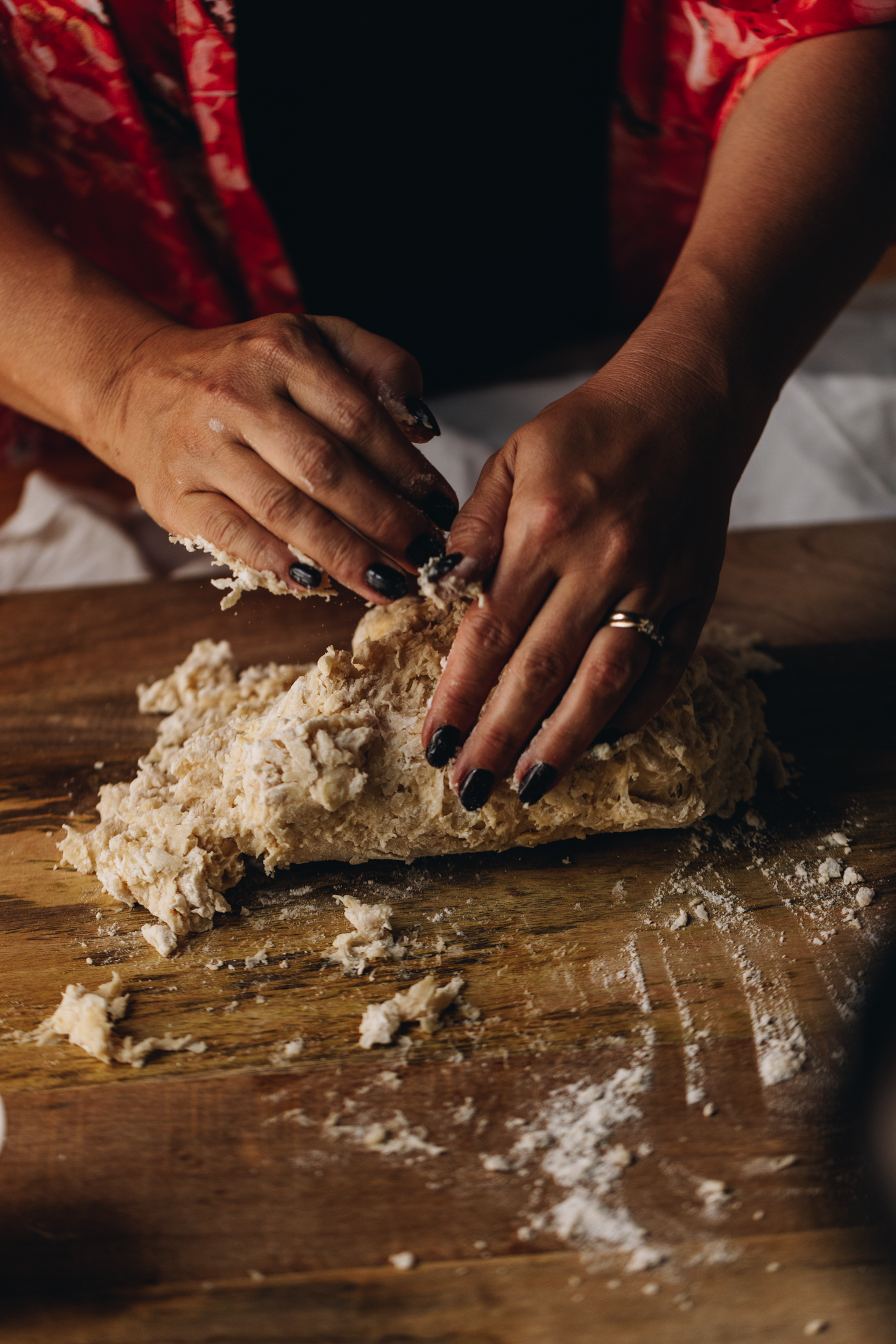 On a wooden board is a milk bread dough that is being knead by hand, by Naomi.