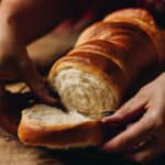 A freshly baked milk bread is being pulled apart by hands revealing the round circle texture inside the bread.