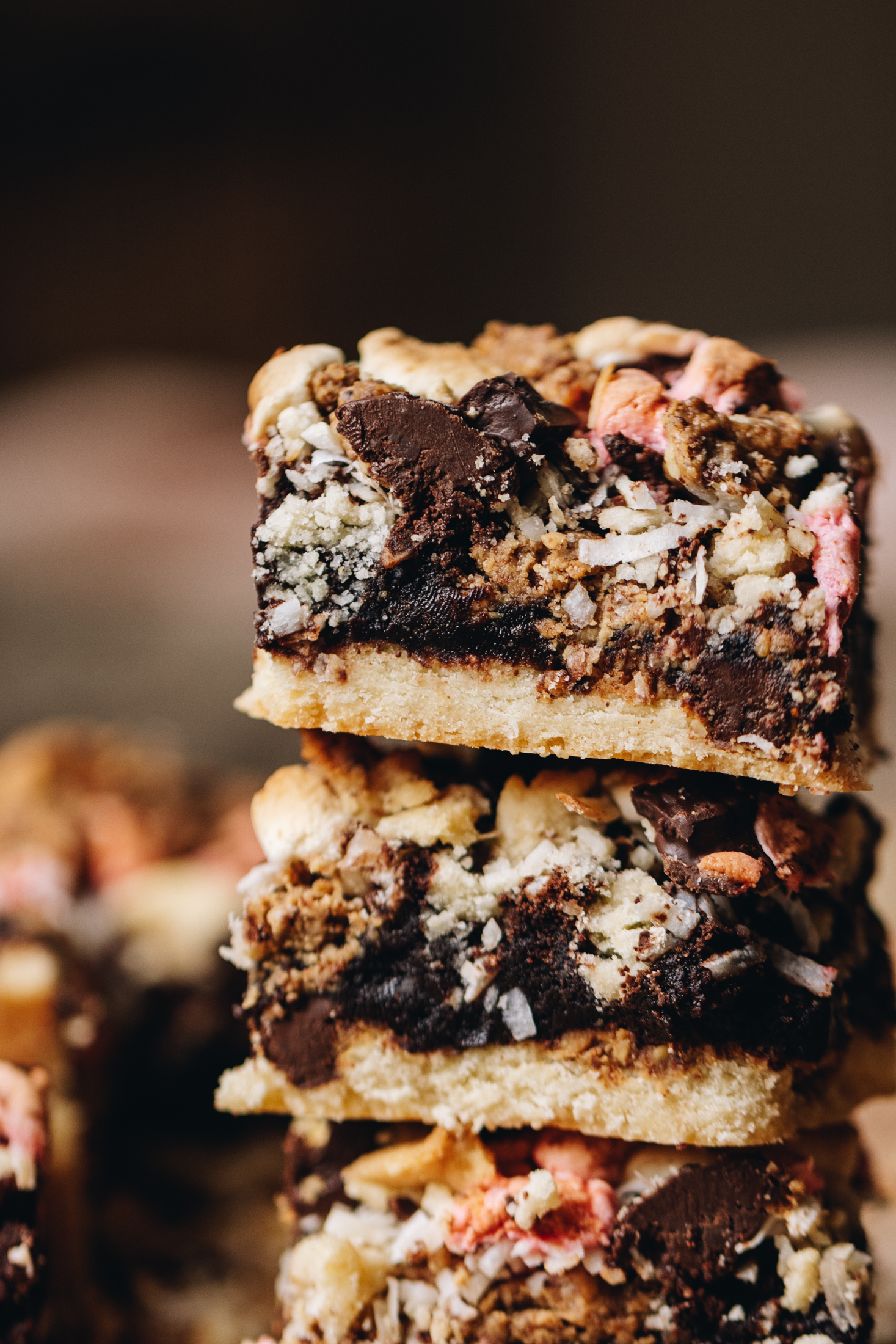 A close up shot reveal three pieces of Brookie slice that have been stacked on top of each other. The shot reveals the cookie base, the brownie centre with peanut butter and chocolate and the marshmallow topping. 