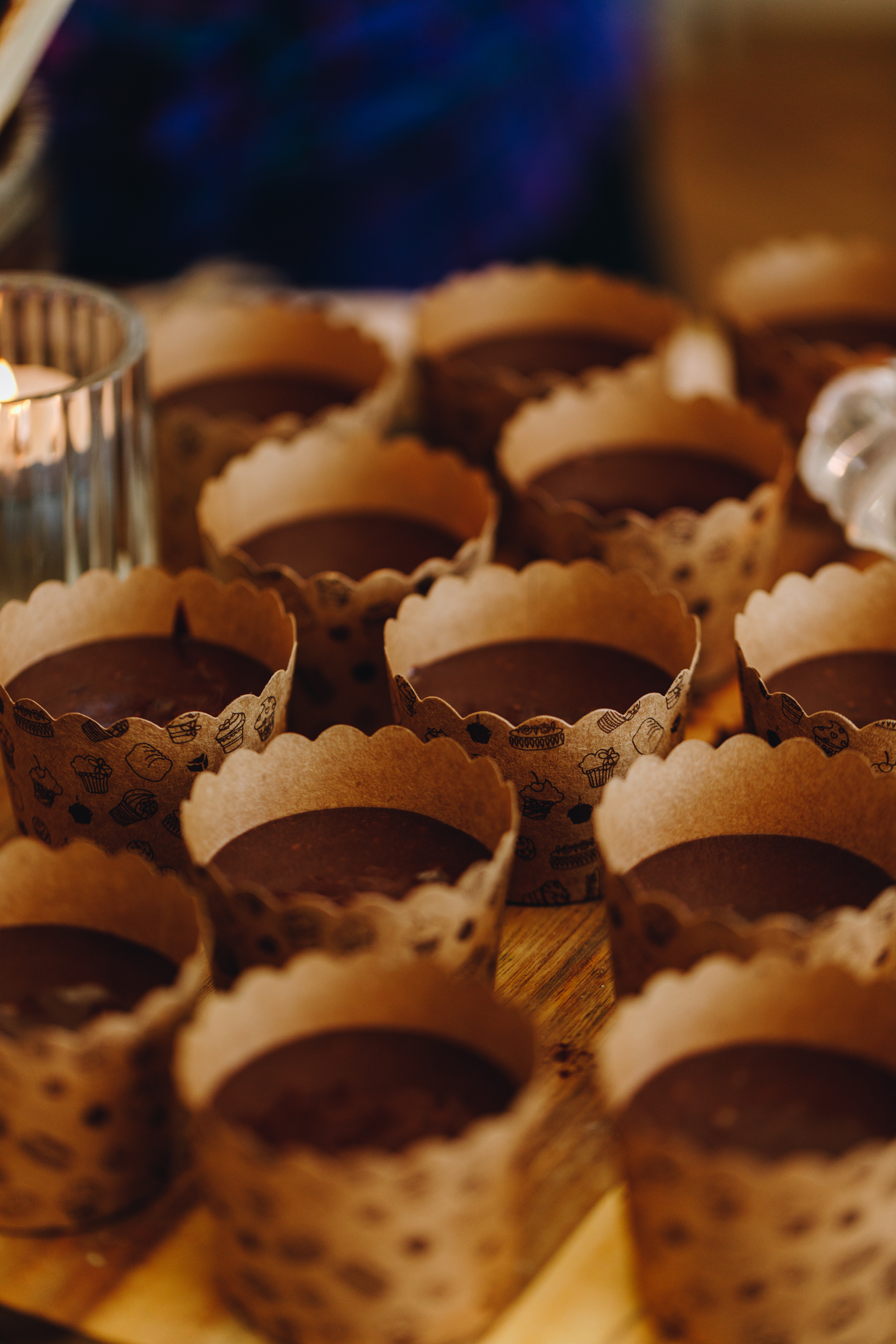 A wooden striped board has brown cardboard cupcake cases with unbaked chocolate muffin batter in it.