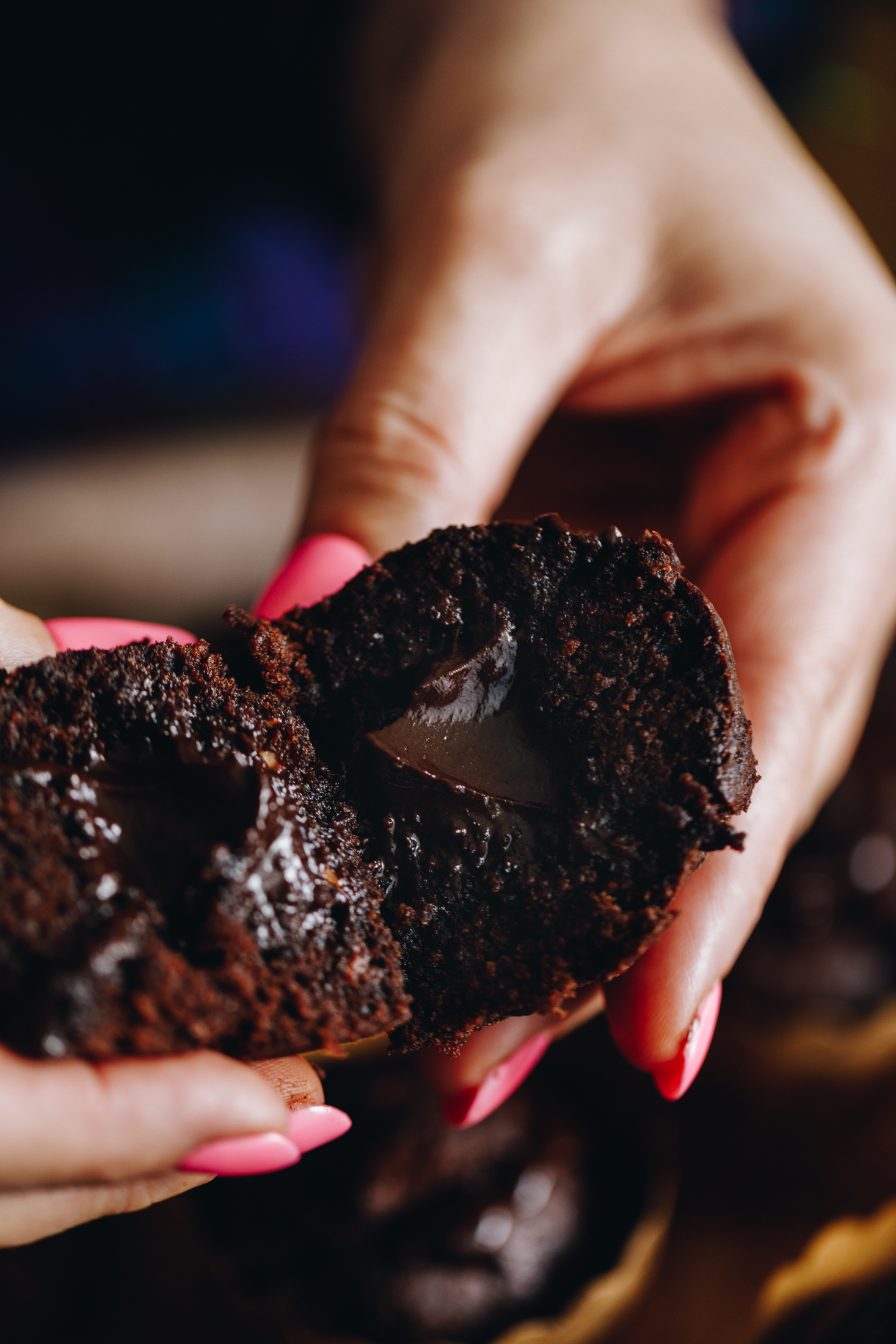 Naomi is holding two pieces of chocolate ganache muffins. The close shot shows the fluffy muffin texture and the gooey chocolate ganache in the centre. 