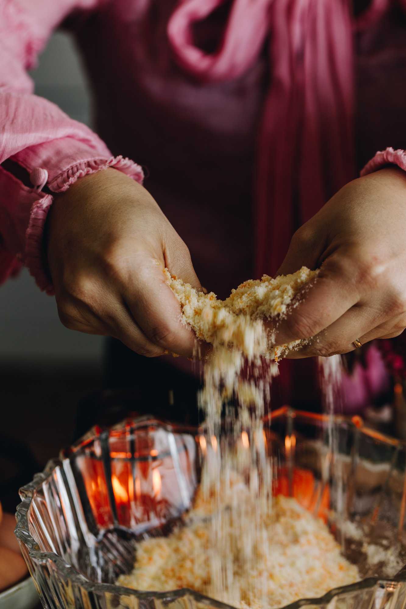 The sugar and mandarin zest for the Raspberry Lamington Cake is being rubbed together with two hands, the action shows the sugar being rubbed and dropping in to the glass bowl.