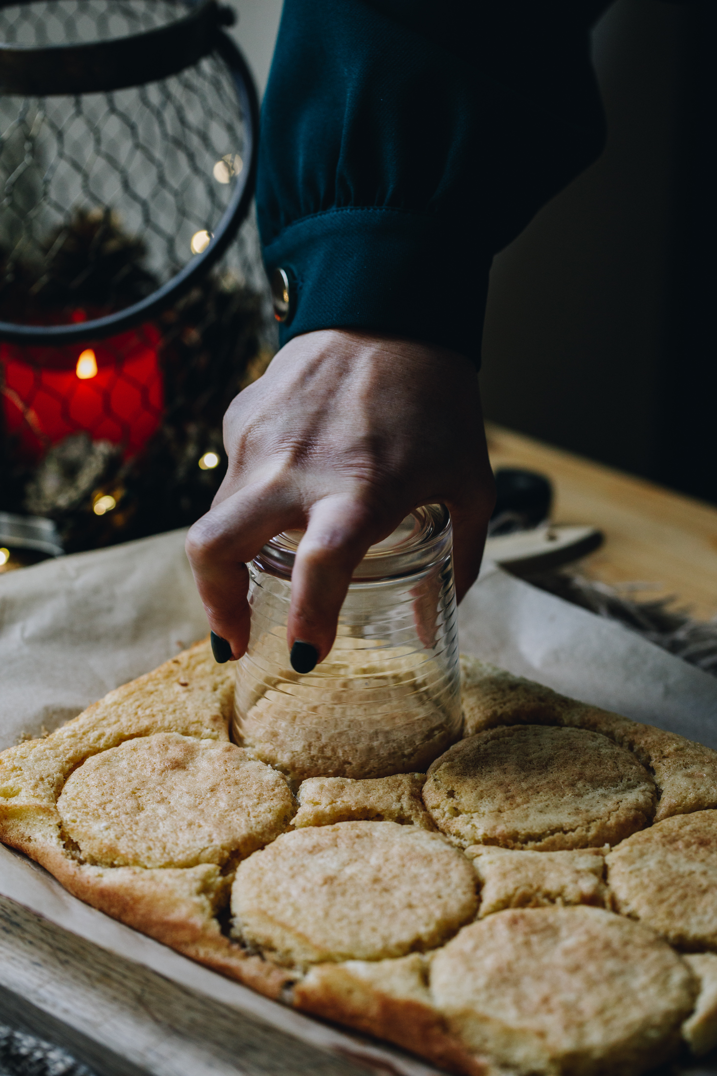 On a silver tray covered with brown paper sponge is being cut out in to rounds with a glass for the mini berry trifles.