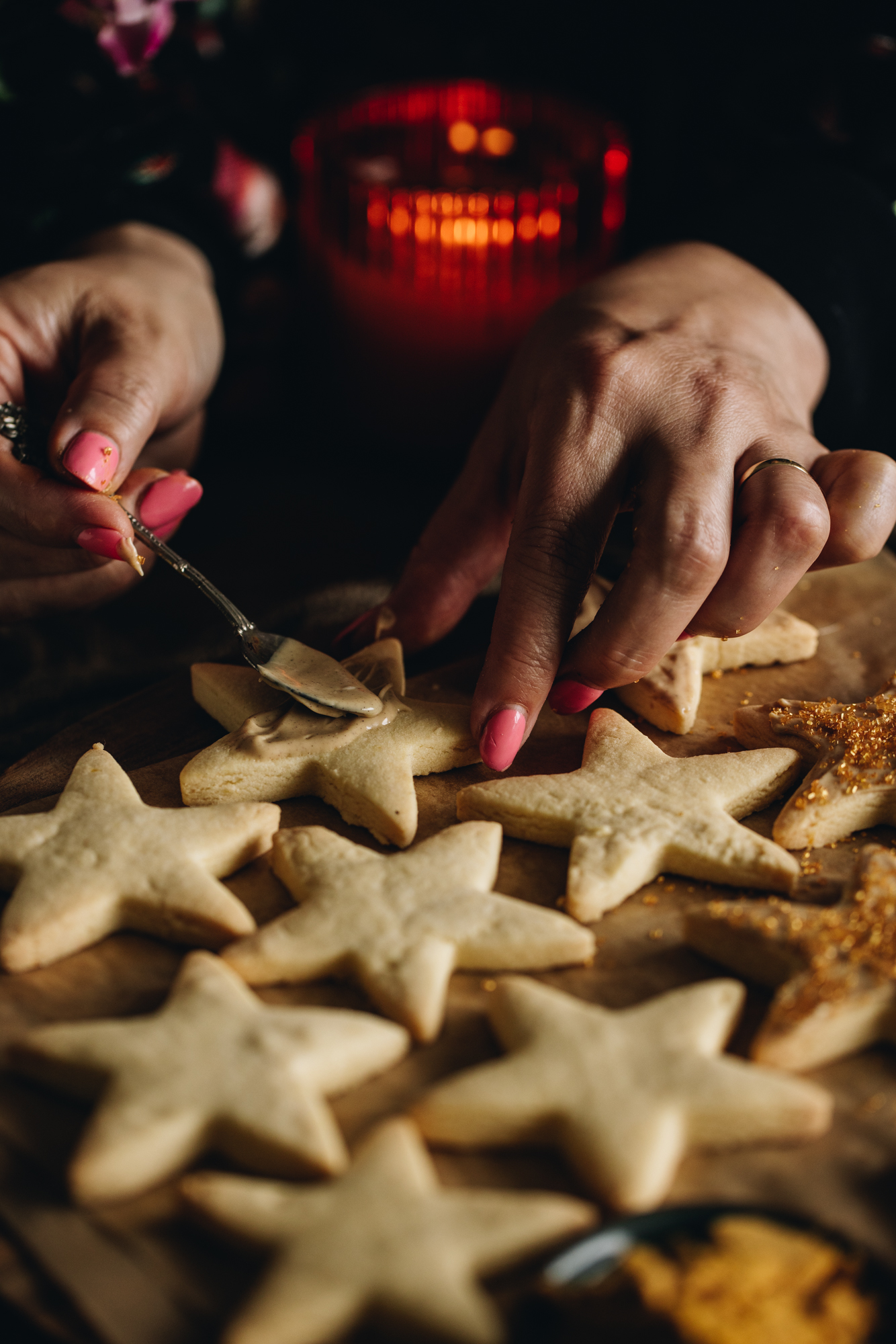 On brown baking paper is freshly baked lemon shortbread cookies. Most of them are plain but Naomi is decorating with by smearing white chocolate on top of it. 
