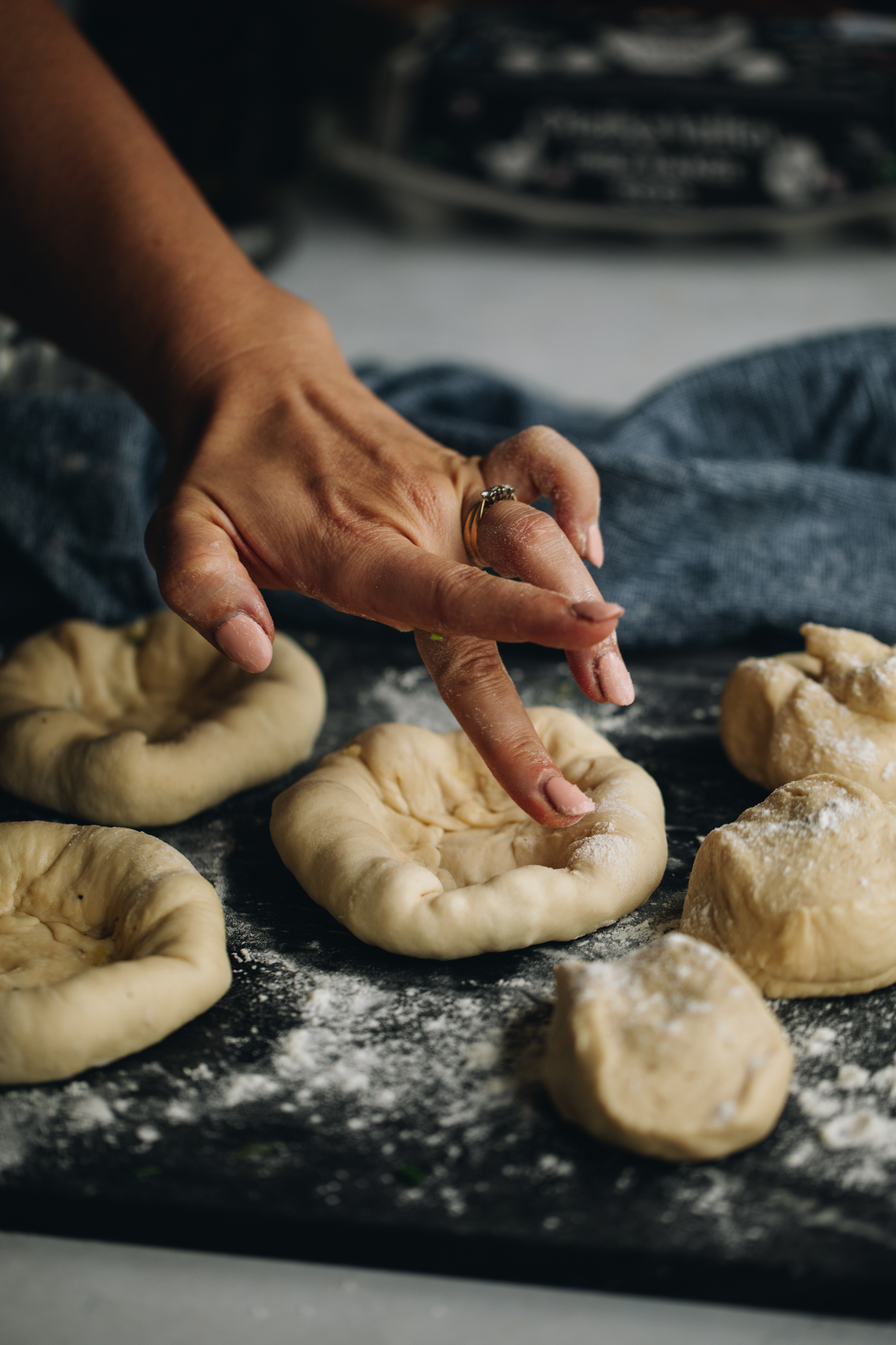 On a blue stone bench are pieces of the Bacon and egg bun dough. They have cheesy stuffed crusts that are being pressed to seal.
