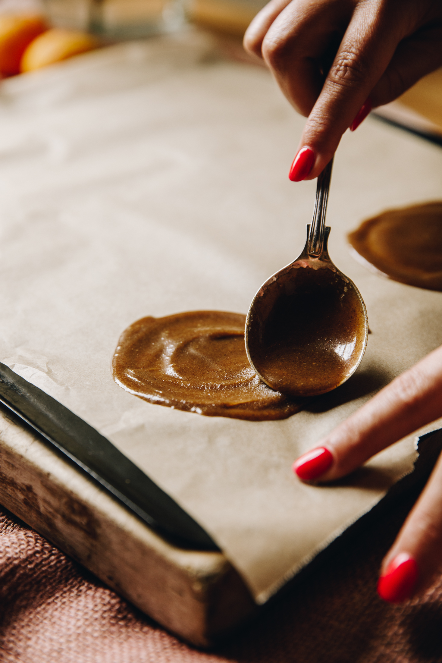 The unbaked biscuit mixture is being spread in to a circle on to baking paper on a wooden table. 