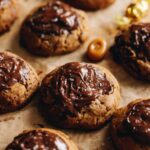 Close up of dark chocolate molasses cookies are freshly baked and iced with dark chocolate and a sprinkle of flaky sea salt.