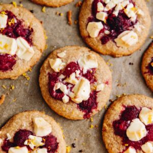 Close up, flat lay shot of freshly baked White Chocolate and Raspberry Biscuits spaced out on baking paper.