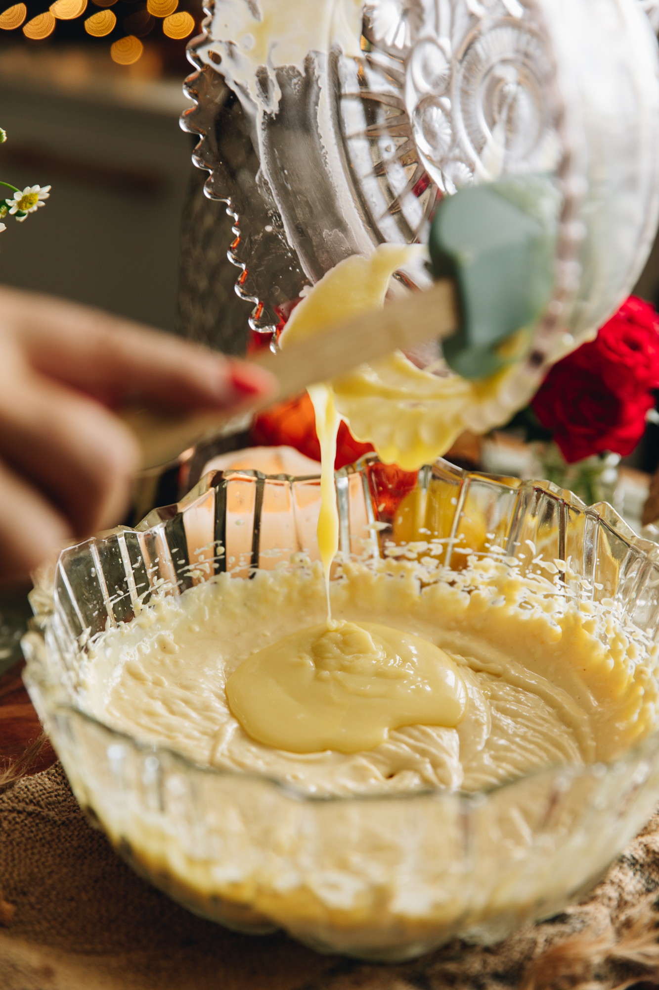 The melted white chocolate filling is being added in to the lemon and white chocolate cheesecake filling. from one bowl to another.