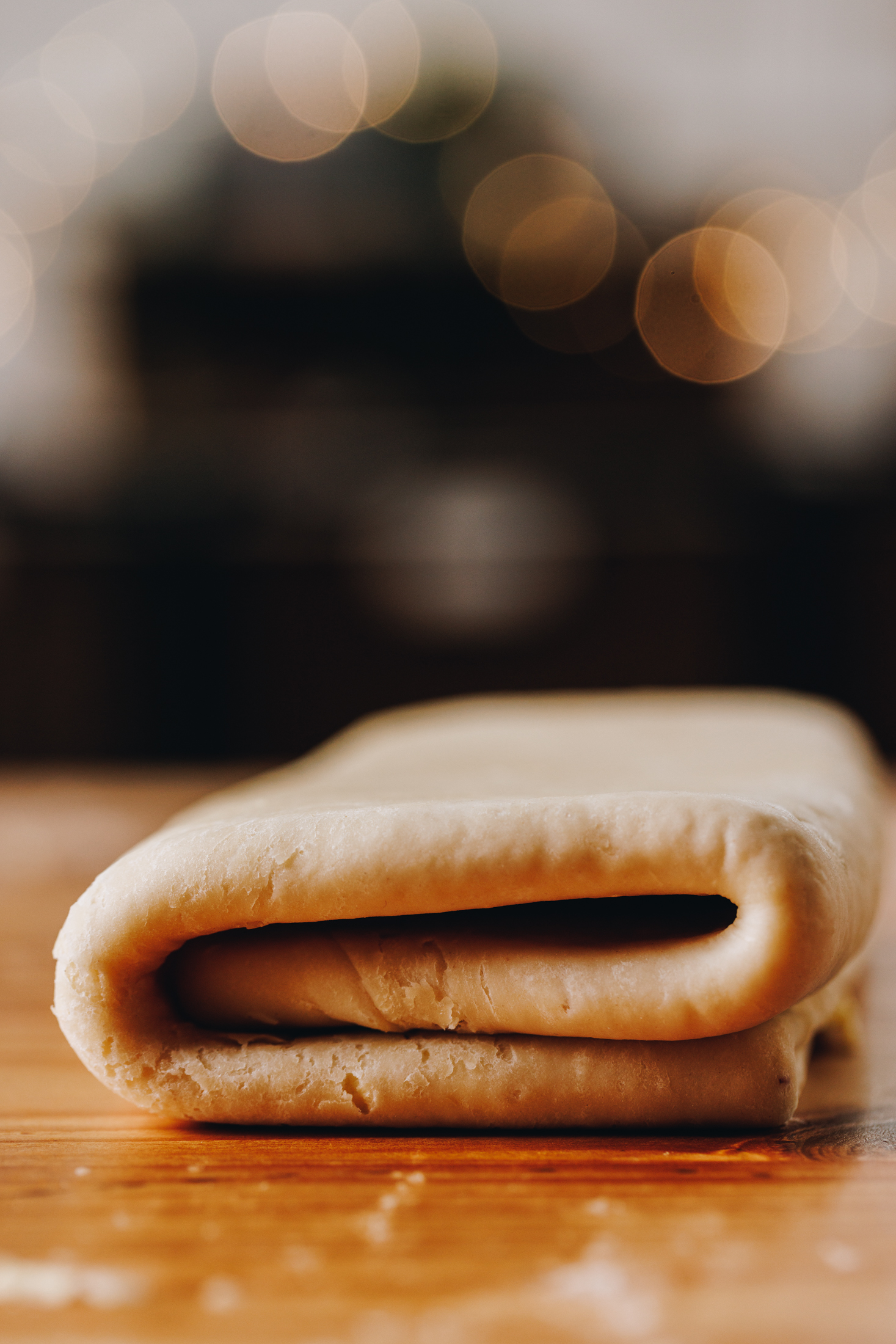 A close up of a folded crunchy yeasted savoury pastry sits on a wooden table. 