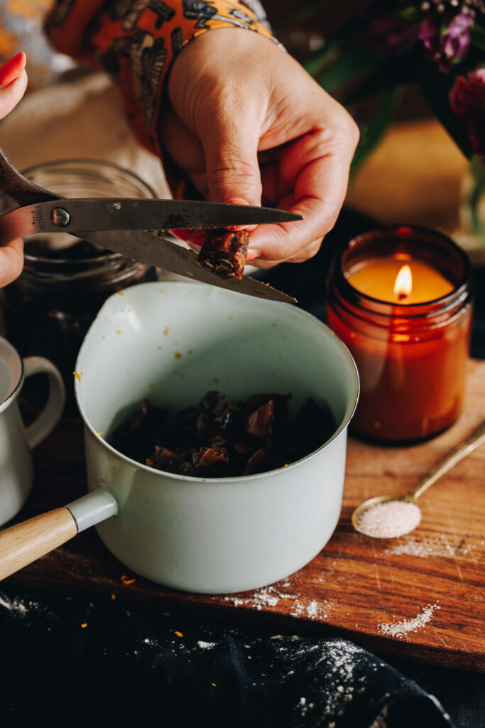 A pair of scissors are cutting dates in to a small pot in preparation for the Date and Orange Scones. 
