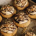 A full of tray of freshly baked and decorated ultimate peanut butter cookies on baking paper.