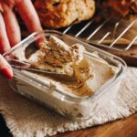 Whipped brown butter has been set in a small glass container, it is on a cream cloth with scones in the background.