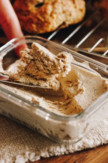 Whipped brown butter has been set in a small glass container, it is on a cream cloth with scones in the background.