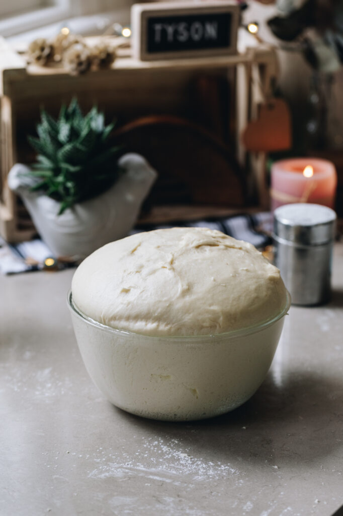 The Light and Fluffy Fry Bread dough is in a glass bowl and the dough has risen above the bowl. 