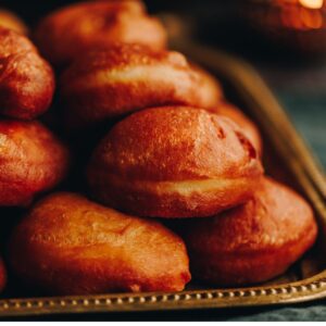 A pile of freshly fried light and fluffy fry bread sit on a golden tray.