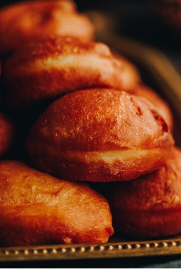 A pile of freshly fried light and fluffy fry bread sit on a golden tray.