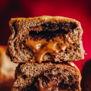 A close up of two biscoff hot cross buns piled on top of each other that reveals the gooey biscoff centre oozing out.