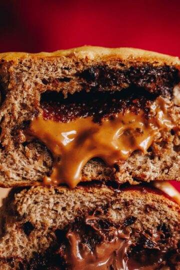 A close up of two biscoff hot cross buns piled on top of each other that reveals the gooey biscoff centre oozing out.