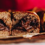 Close of Nutella Hot Cross Buns that have been sliced open and really gooey Nutella come out of the centre of the buns.