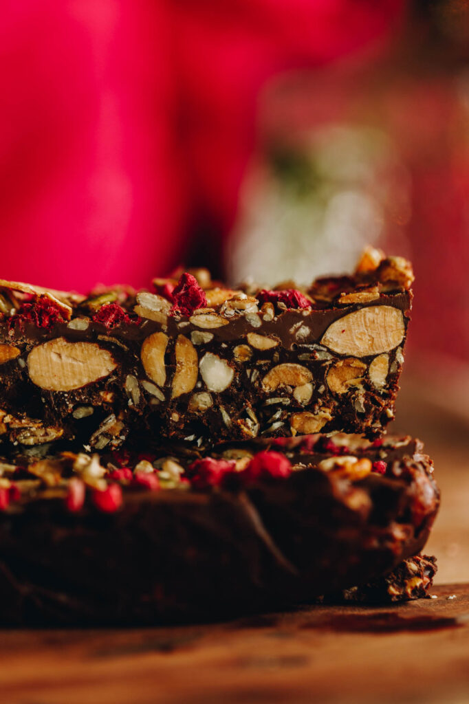A close up of a slice of chocolate nut and seed slice. The texture shows all the nuts inside the bar. 