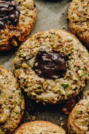 A close shot of 5 Pistachio and chocolate cookies reveal the gooey chocolate centre.