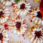 Fresh strawberry jam drops have been decorated with meringue and are sitting on white baking paper.