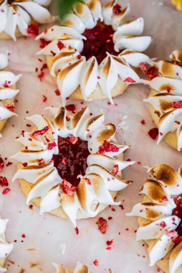 Fresh strawberry jam drops have been decorated with meringue and are sitting on white baking paper.