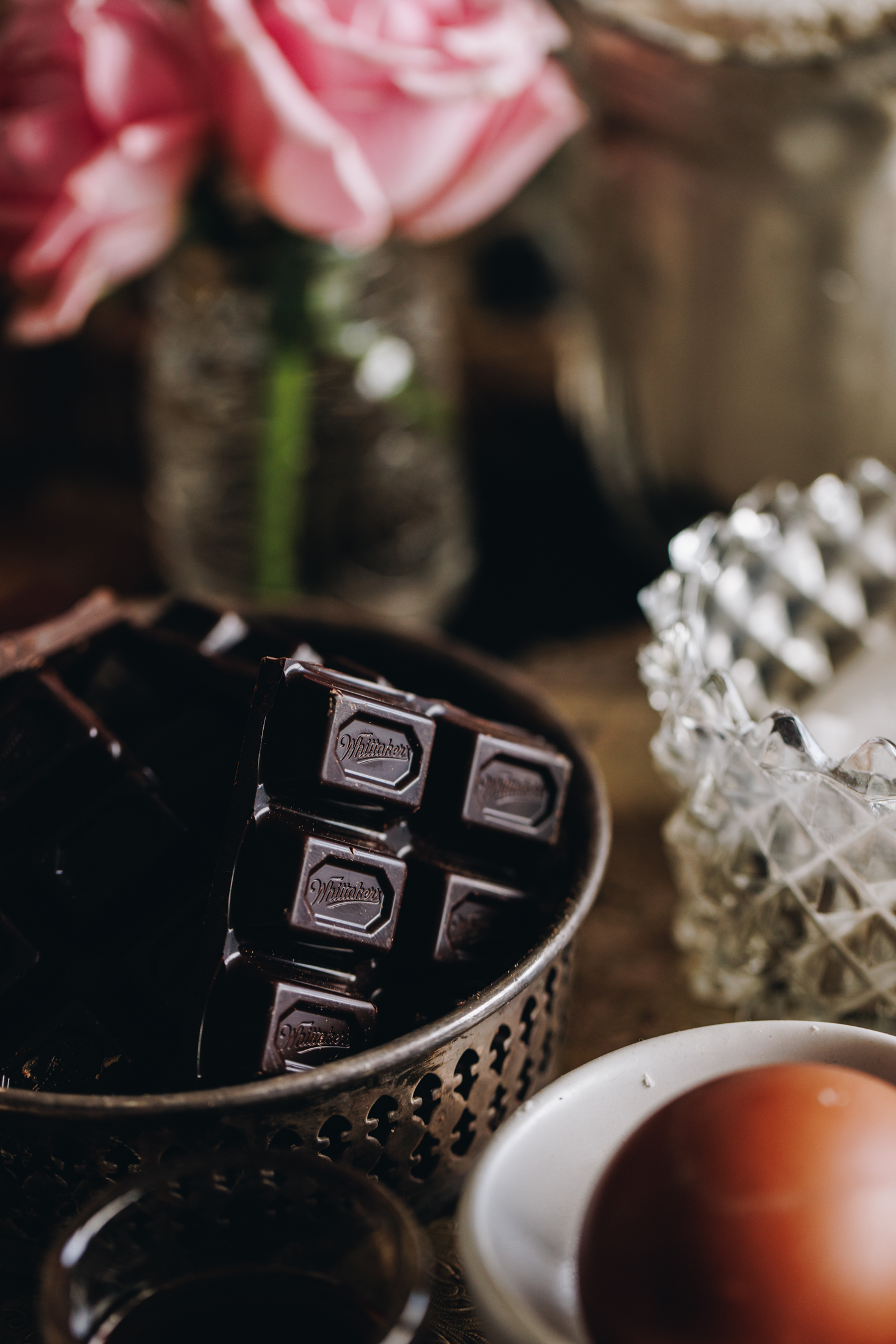 Close up dark chocolate and eggs with pink flowers in the background.