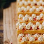White chocolate yogurt cream piped on to lemon bars with a sprinkle of freeze dried raspberries on top.