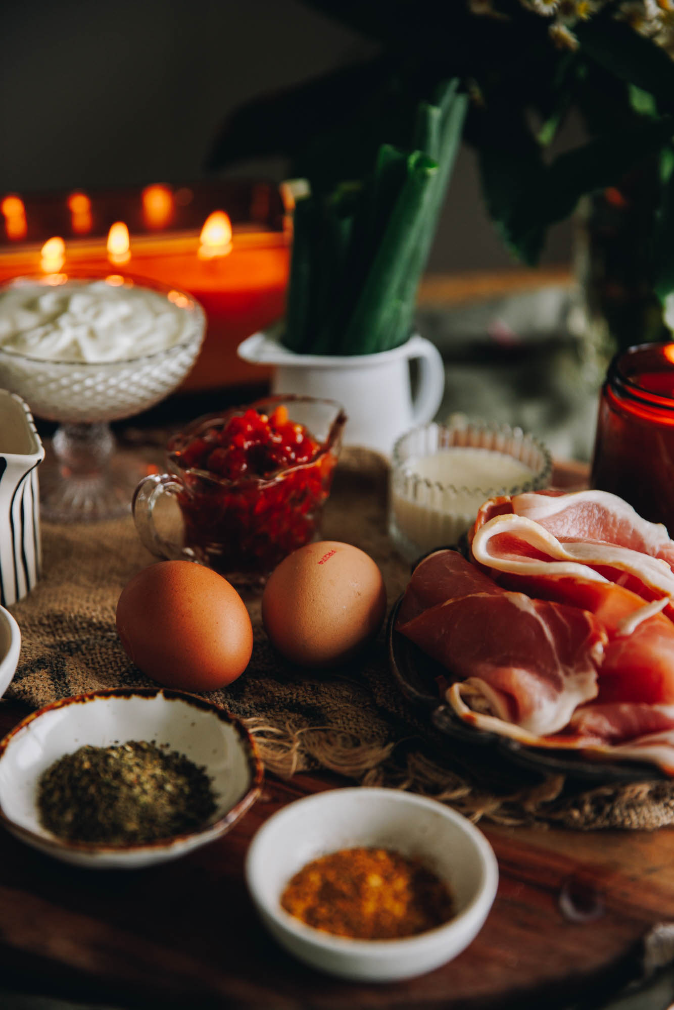 Cheesy Bacon Savoury Muffins ingredients are on a wooden board in vintage cups, spoons and bowls.