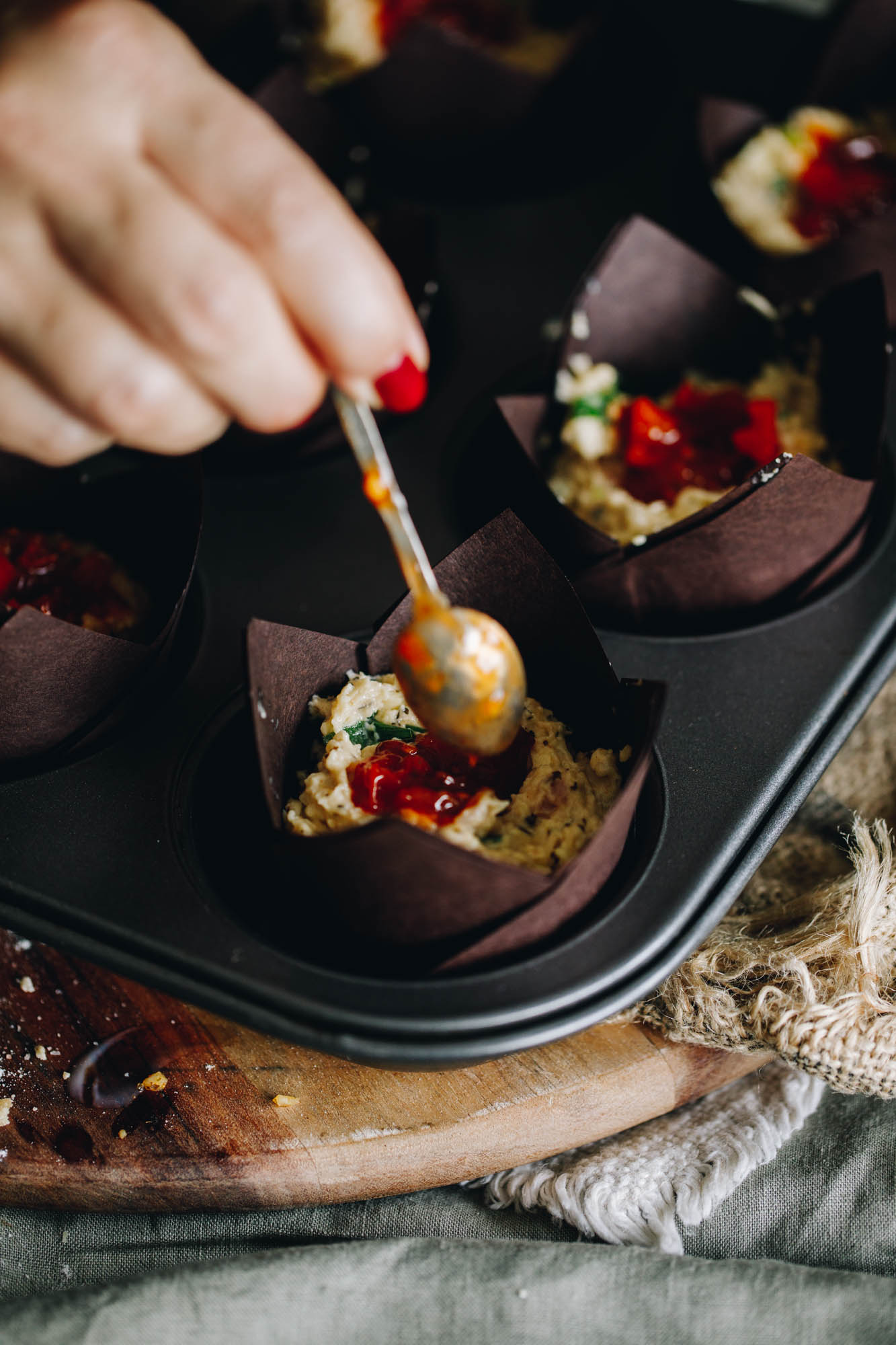 Tomato chutney is being added in to the centre of a savoury muffin.