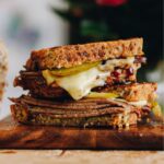 A close up of toasted sandwich with meat and melty cheese shows the Kneaded seeded loaf as a toastie.