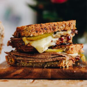 A close up of toasted sandwich with meat and melty cheese shows the Kneaded seeded loaf as a toastie.