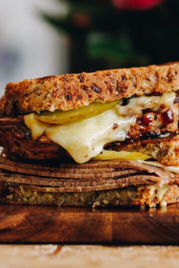 A close up of toasted sandwich with meat and melty cheese shows the Kneaded seeded loaf as a toastie.